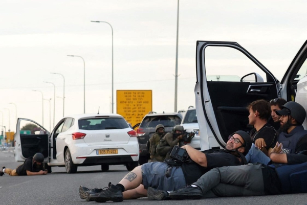 Periodistas se refugian detrás de automóviles mientras los soldados israelíes toman posiciones durante los enfrentamientos con combatientes palestinos cerca del kibutz Gevim, cerca de la frontera con Gaza. Foto: Oren ZIV / AFP.