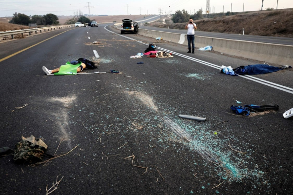Un hombre toma una fotografía de muertos esparcidos a lo largo de una carretera tras una infiltración masiva de pistoleros de Hamas desde la Franja de Gaza, en la zona de Sderot, al sur de Israel, Foto: REUTERS/Ammar Awad.