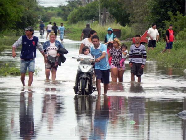<p>Pobladores del Barrio "Carpincho Macho" de Resistencia, transitan el camino de acceso al barrio, completamente inundado por las intensas lluvias. Foto: Fabián Maldonado </p>