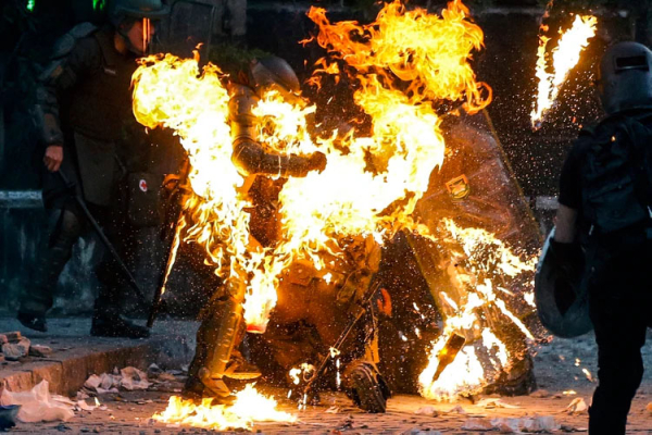 Agentes tratan de ayudar a quienes fueron alcanzados por una bomba molotov (AFP)