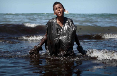 La impactante imagen de un chico cubierto de petróleo en las playas de Brasil
