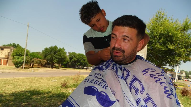 Todo a pulmón: cortan el cabello por $2000 en el parterre de una avenida