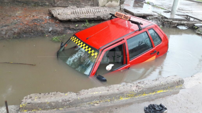 Un radio taxi cayó a una cuneta y quedó tapado por el agua