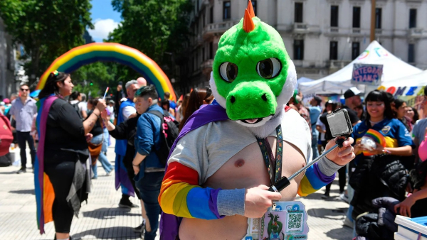 Un hombre con una máscara de dinosaurio se saca una selfie en la marcha.