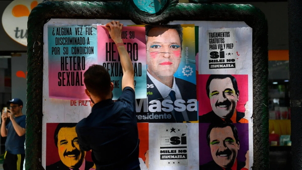 Una persona pega e interviene los carteles de la vía pública al estilo de la manifestación.